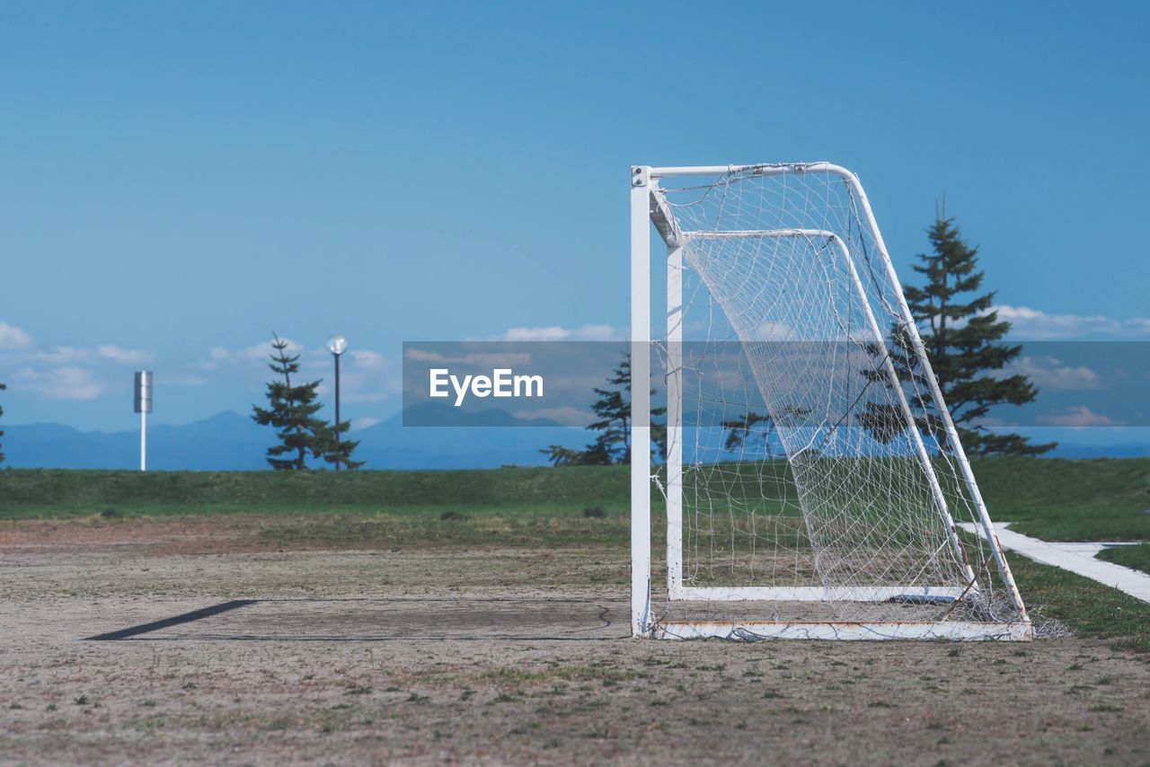 Goal post on soccer field against blue sky