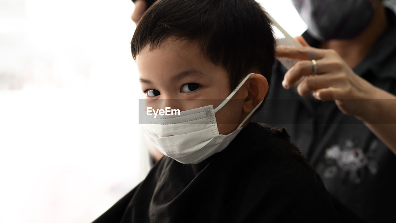 Midsection of man cutting boy hair