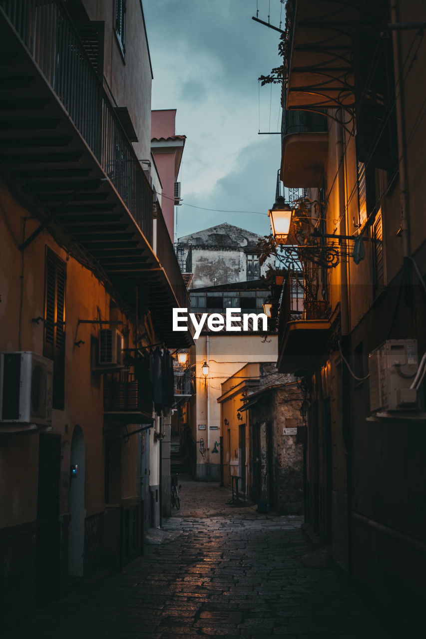 Alley amidst buildings in city at dusk