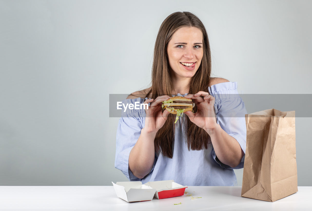 Portrait of smiling young woman sitting on table