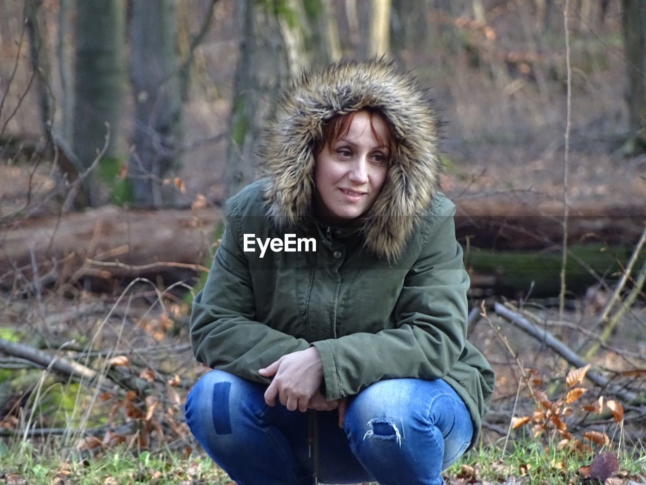 Smiling mid adult woman crouching in forest