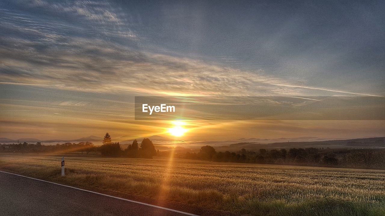 Scenic view of agricultural field against sky during sunset