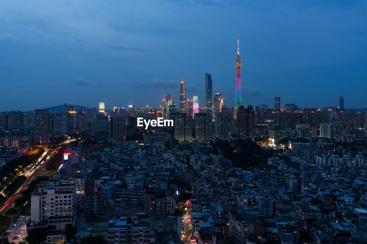 Illuminated modern buildings in city against sky at night