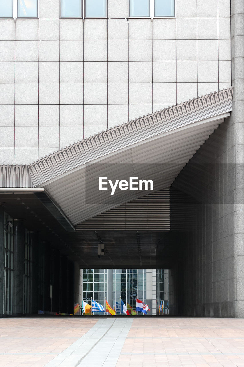 Modern architectural feature with international flags displayed below a geometric facade. 