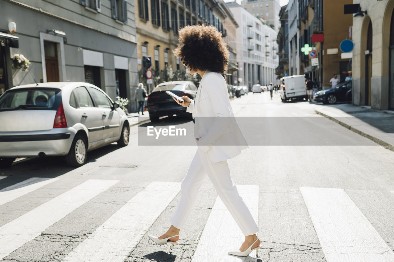 Businesswoman using phone walking on city street