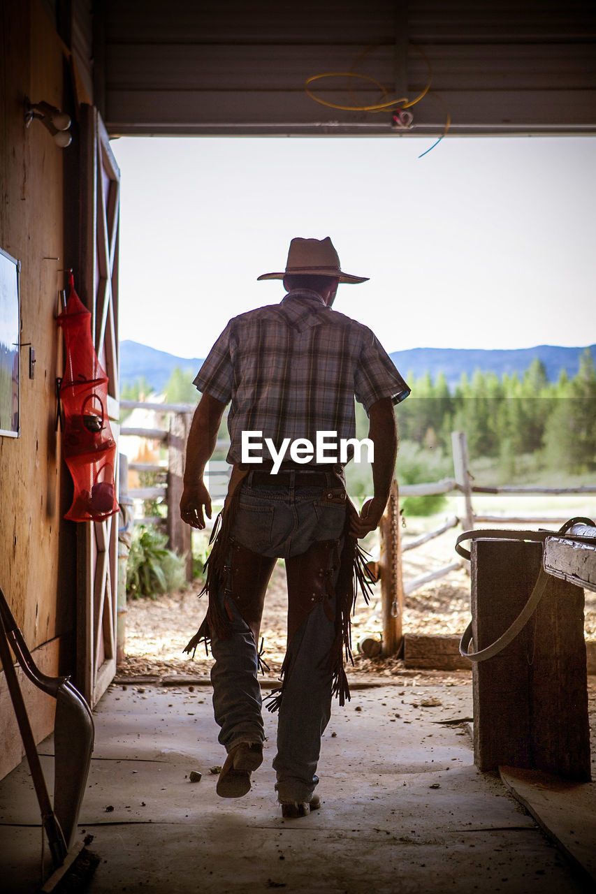 Rear view of man wearing cowboy hat at farm