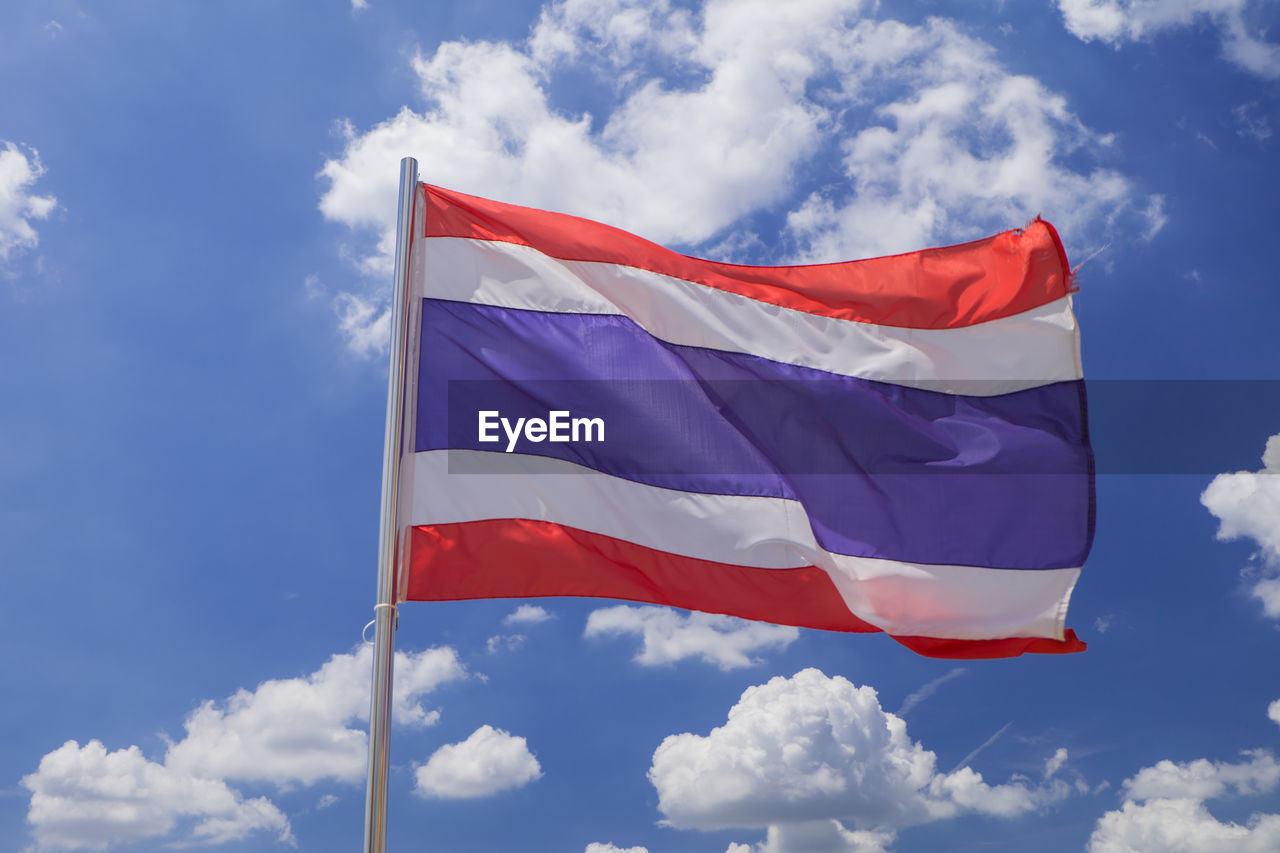 LOW ANGLE VIEW OF AMERICAN FLAG FLYING AGAINST BLUE SKY