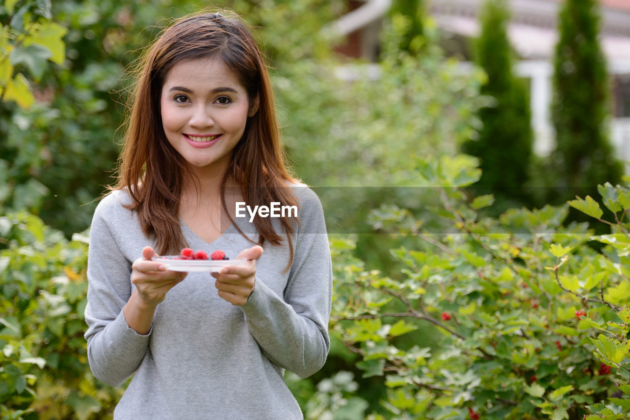 PORTRAIT OF A SMILING YOUNG WOMAN HOLDING ICE CREAM