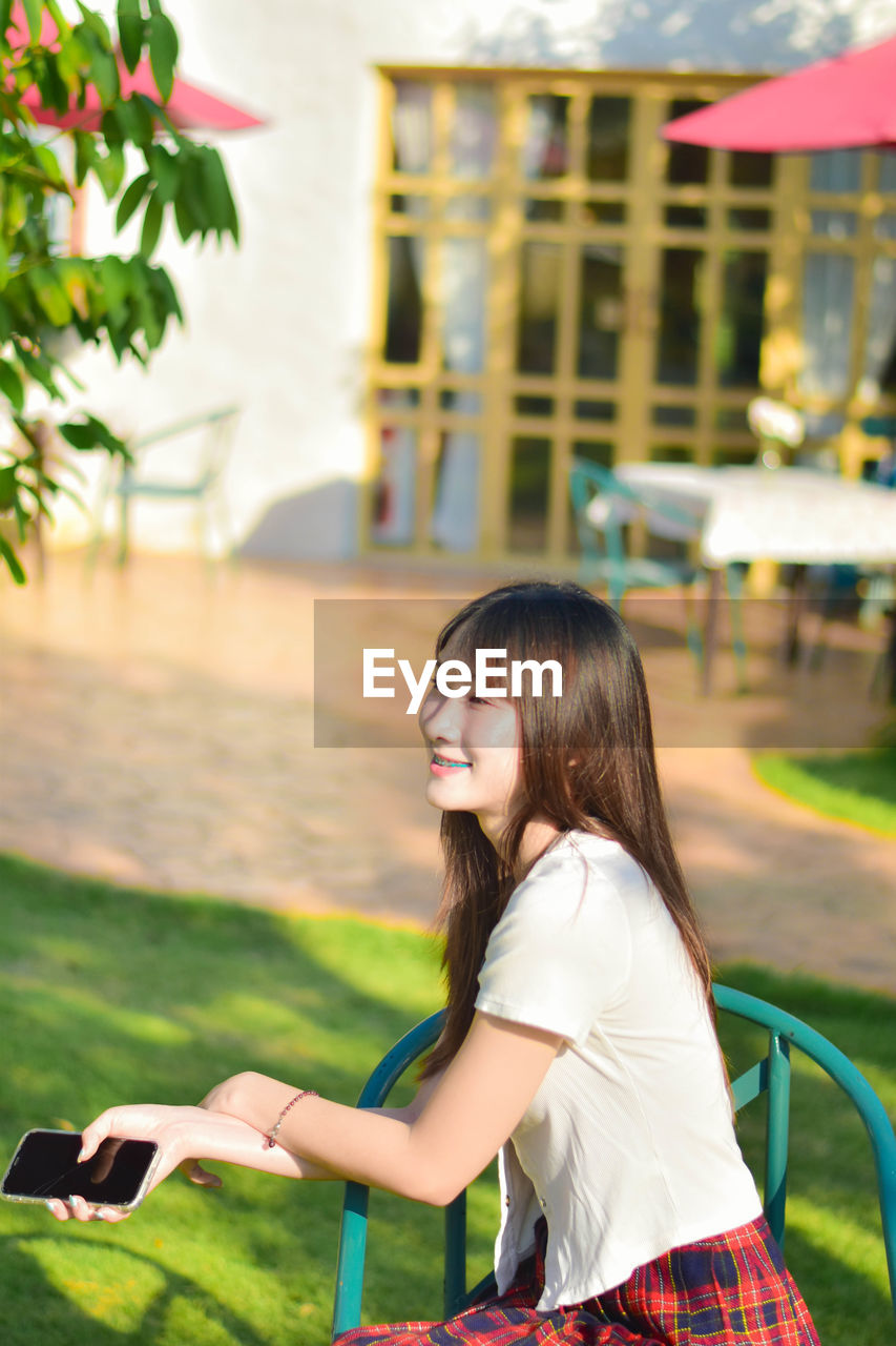 side view of young woman looking away while sitting outdoors