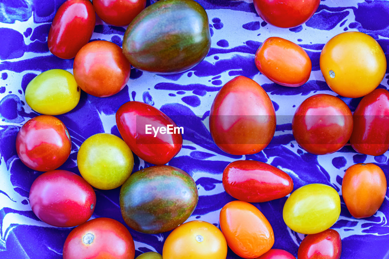 Yellow, red, orange, and dark green heirloom cherry tomatoes on blue spatter enamelware plate