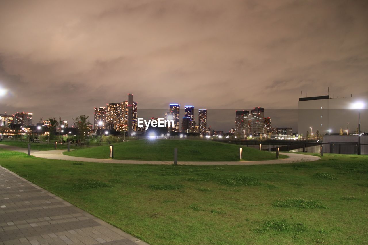 ILLUMINATED PARK BY BUILDINGS AGAINST SKY