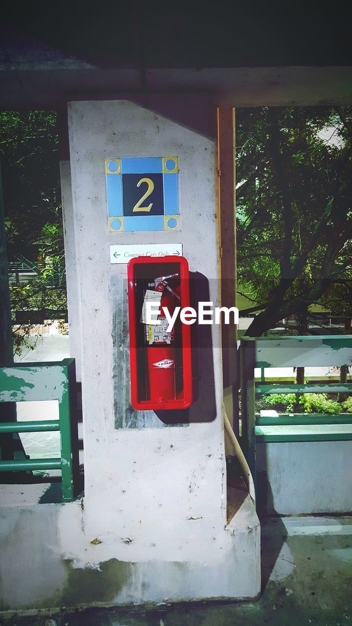 Fire extinguisher mounted on wall against trees