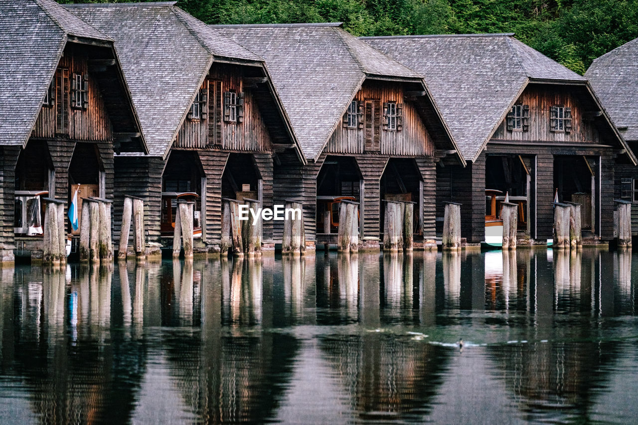 Wooden posts in lake against buildings