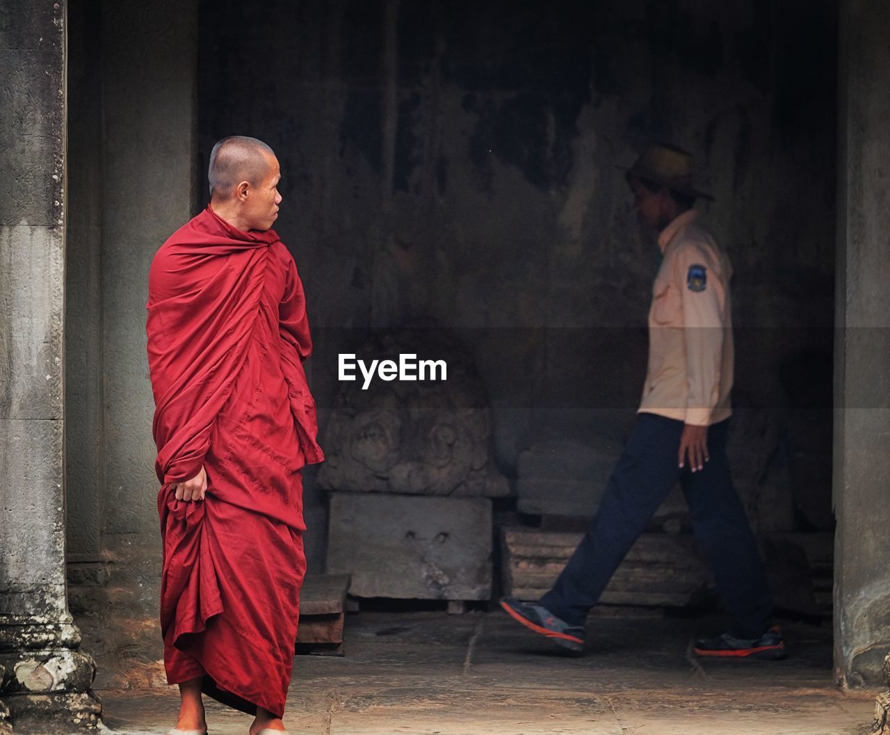 Monk looking at man walking in angkor wat