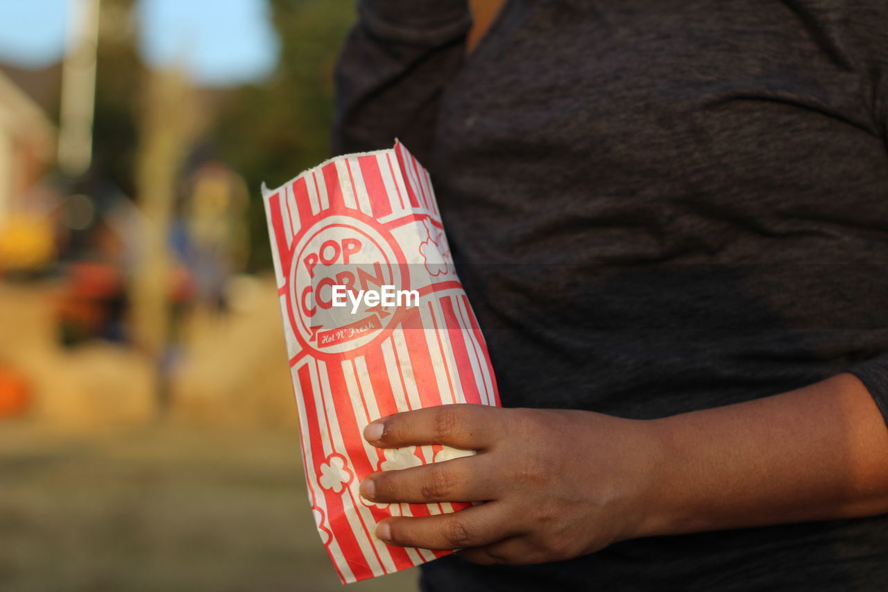 Midsection of man holding popcorn bag