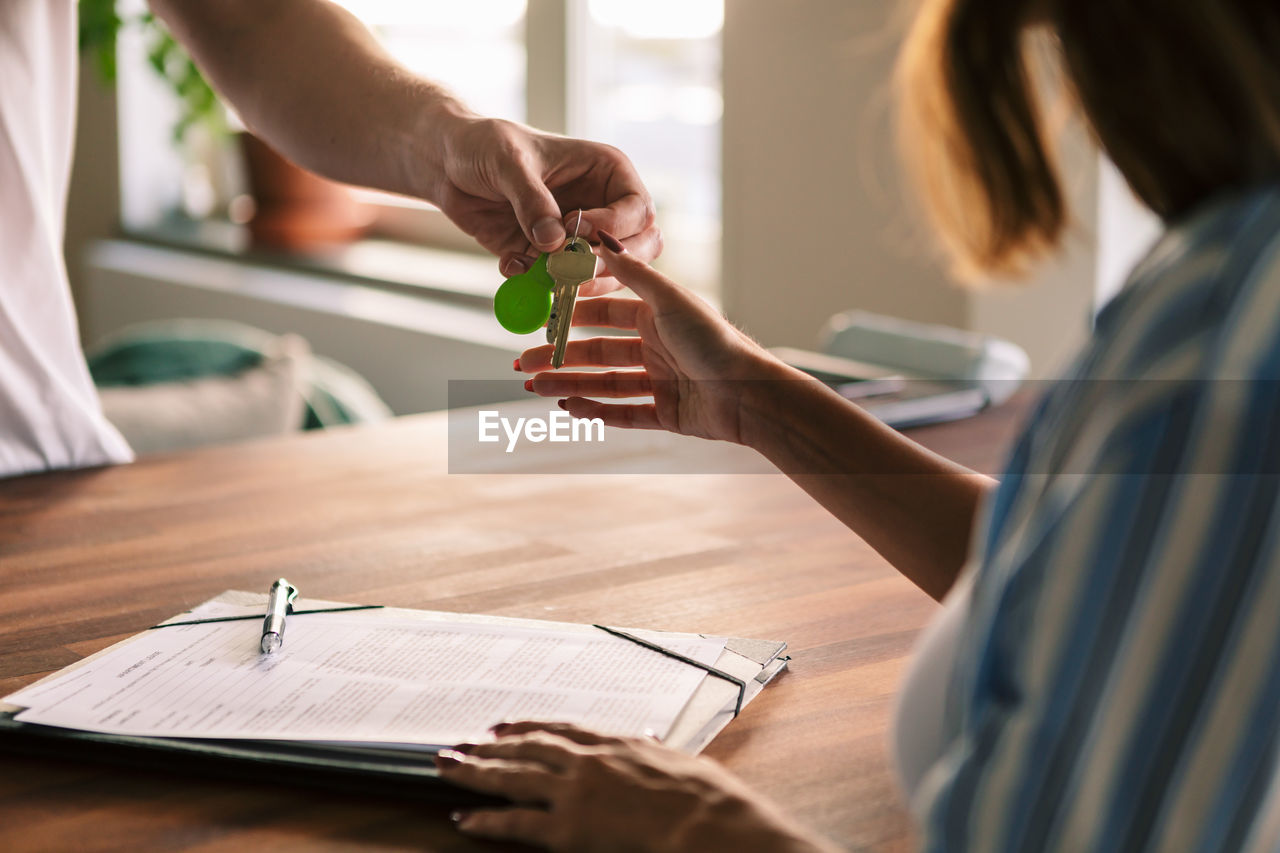 Cropped image of owner giving house keys to tenant after filling rental forms