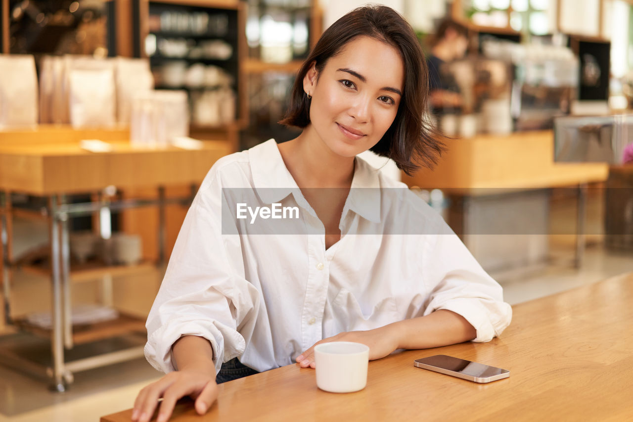 portrait of young woman using mobile phone in cafe