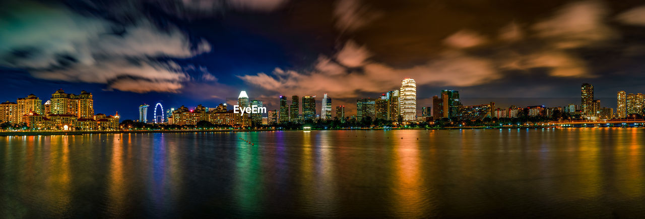 Illuminated city by buildings against sky at night