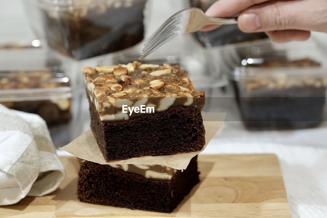 CLOSE-UP OF HAND HOLDING ICE CREAM WITH CAKE