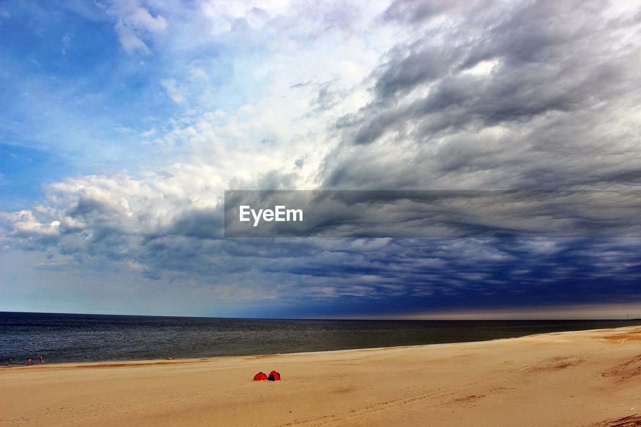 View of calm beach against clouds