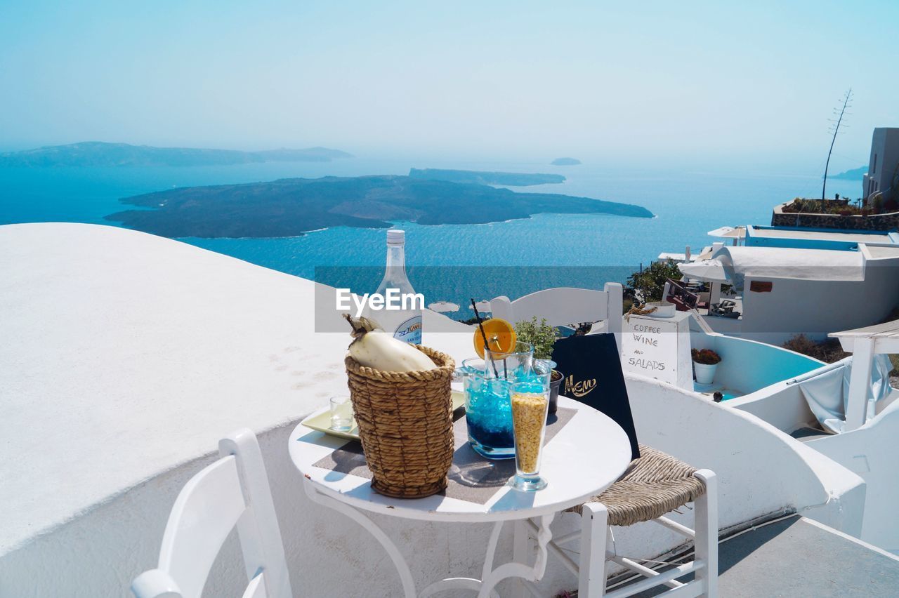 CHAIRS AND TABLE AT SHORE AGAINST SKY