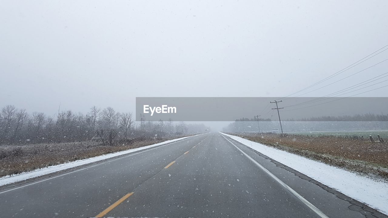 ROAD AMIDST SNOW AGAINST SKY DURING WINTER