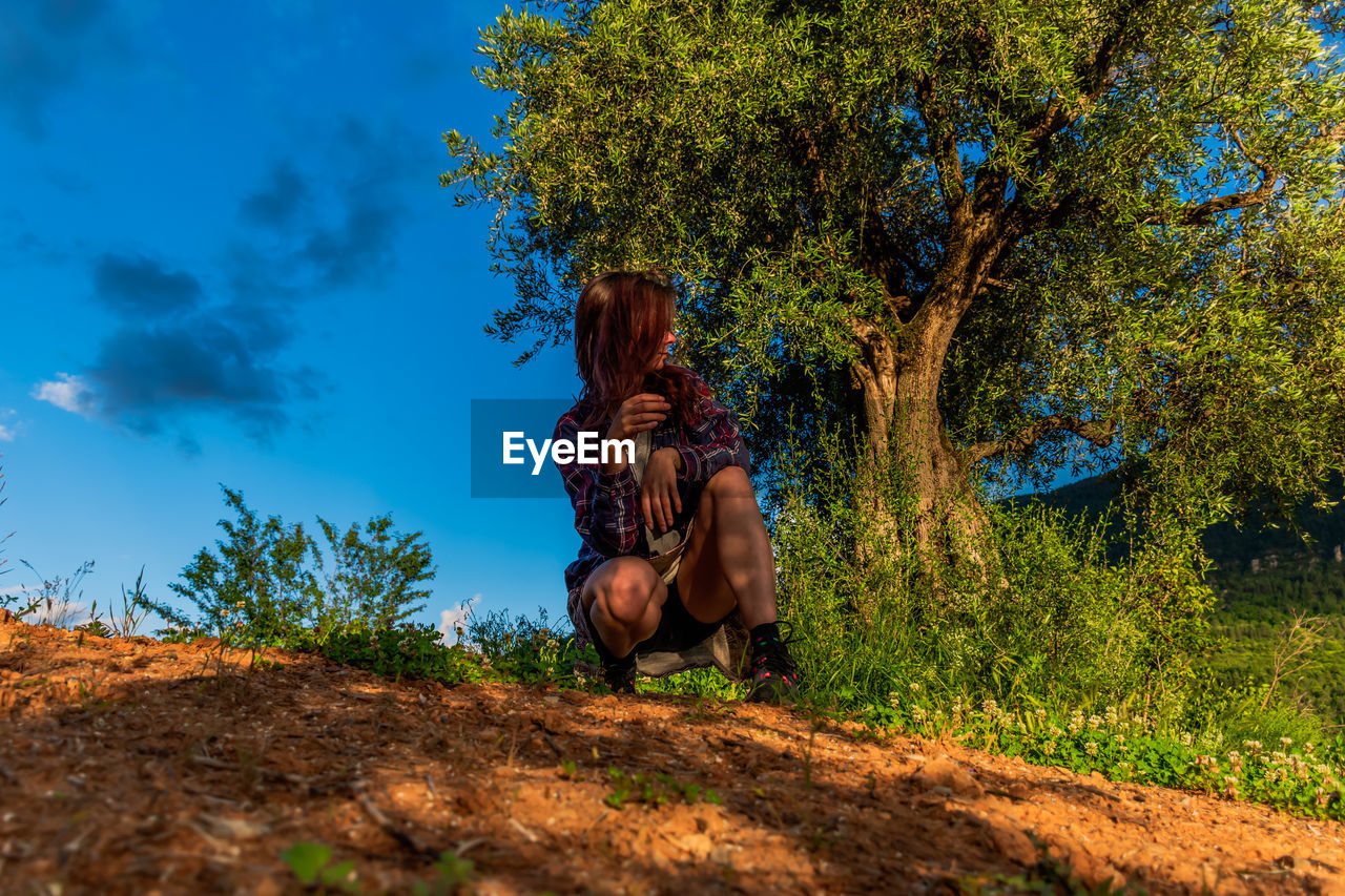 FULL LENGTH OF WOMAN SITTING OUTDOORS