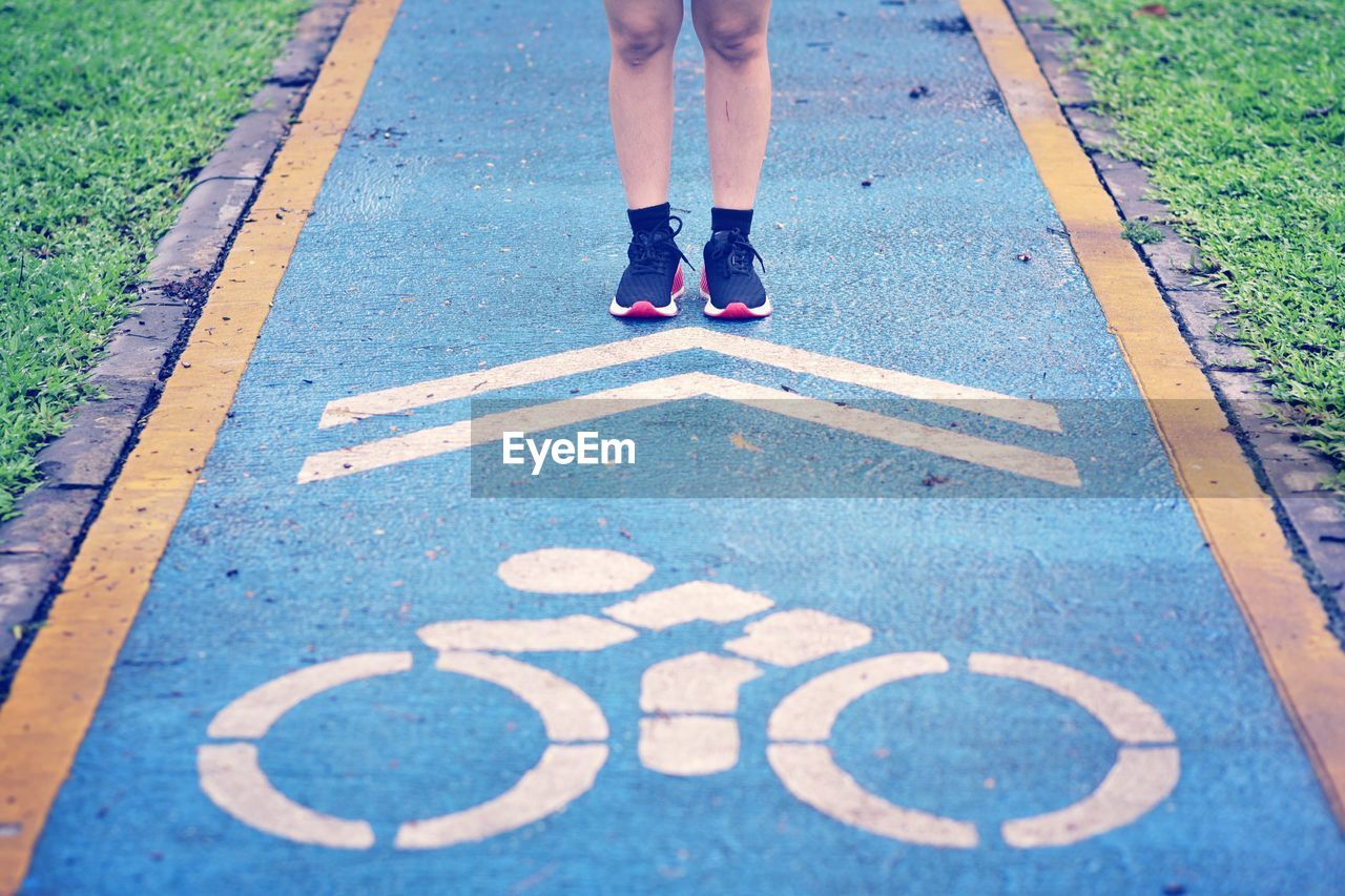 Low section of woman standing on footpath