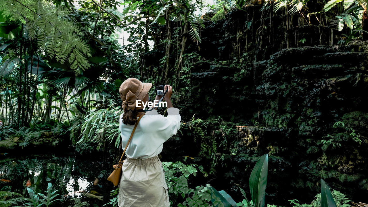 REAR VIEW OF WOMAN PHOTOGRAPHING WITH CAMERA