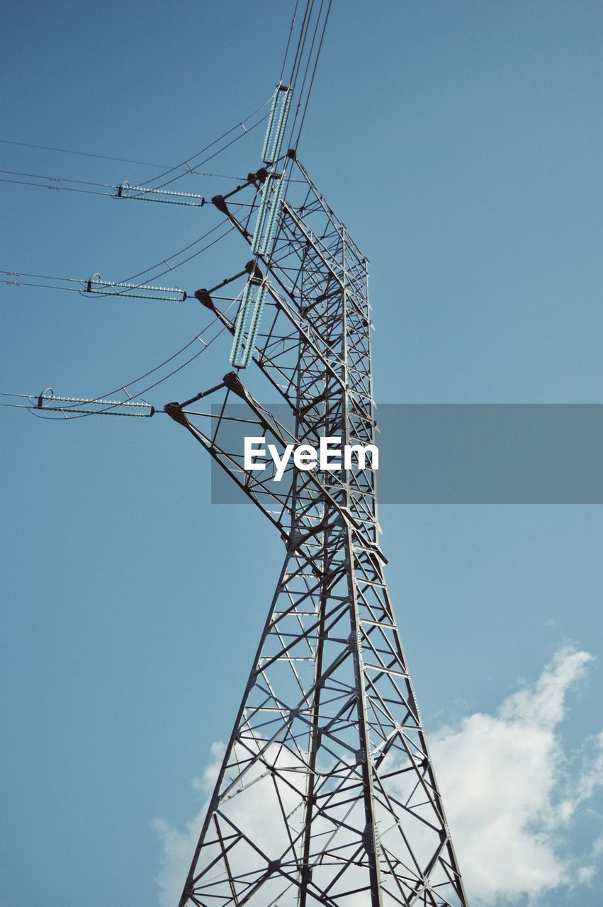 Low angle view of electricity pylon against blue sky