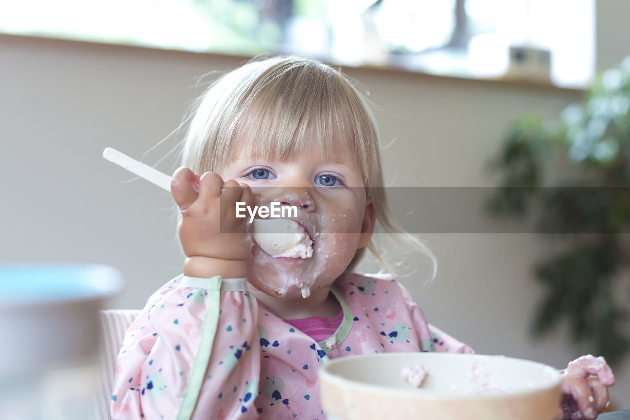 Cheerful cute girl eating ice cream at home