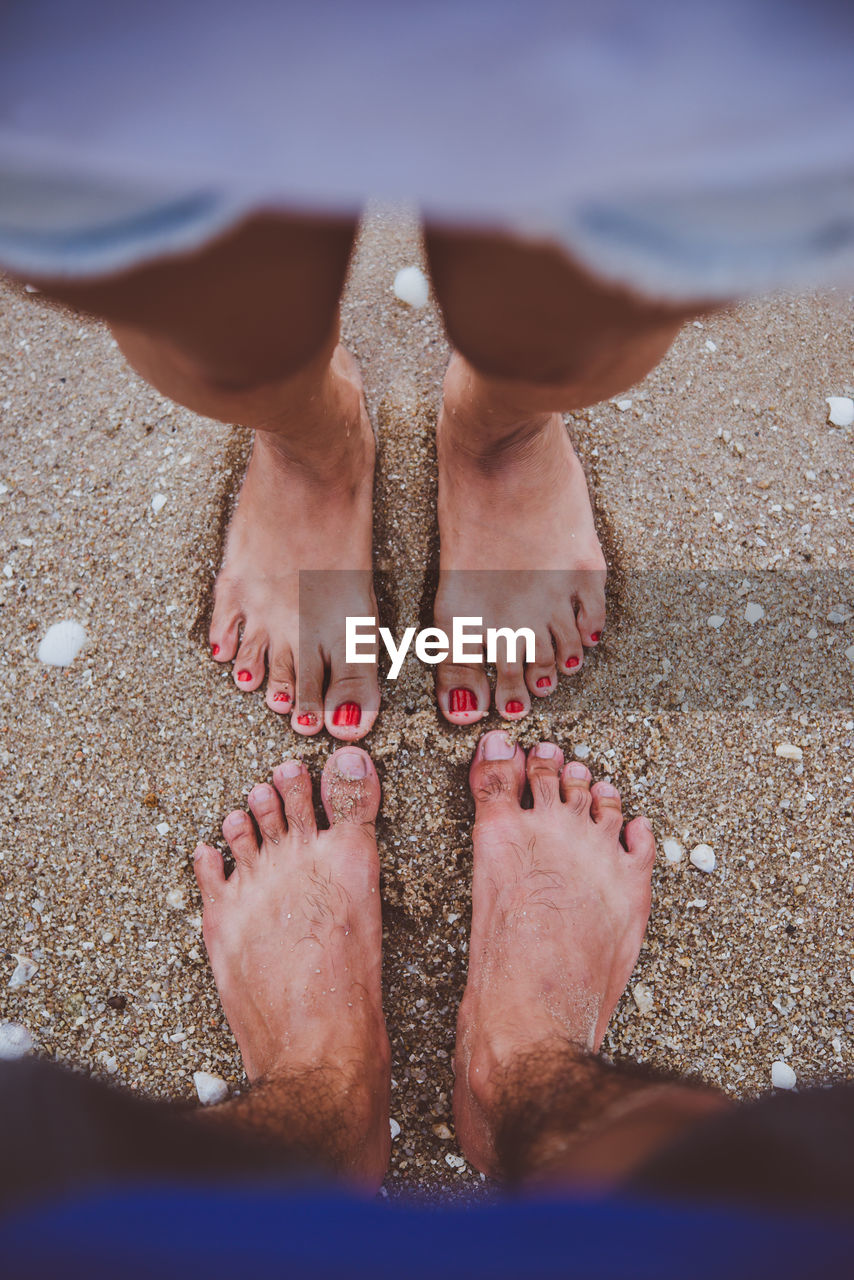 Low section of man and woman standing on beach