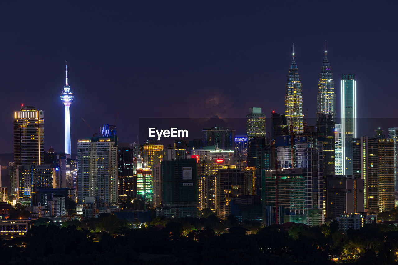 Illuminated buildings in city against sky at night