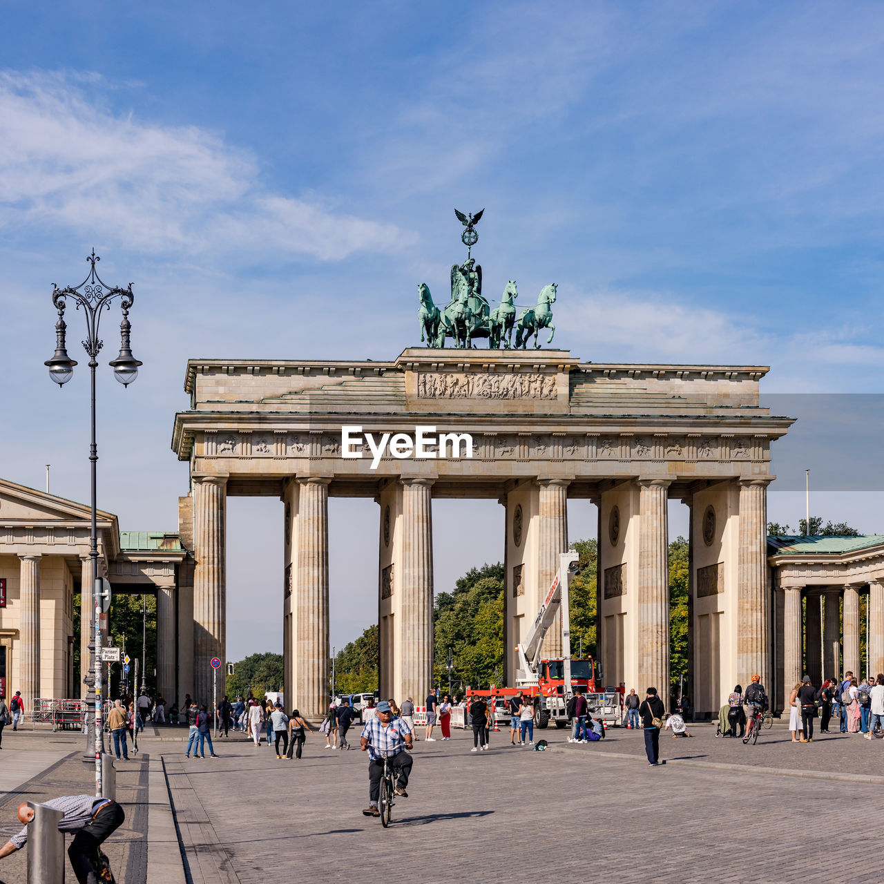 The brandenburg gate with street lamp and people as german landmark under blue sky, berlin, germany