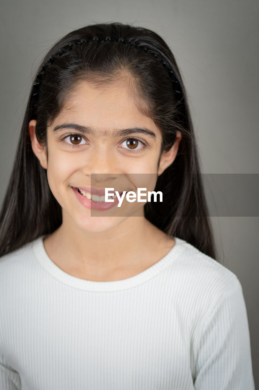 Portrait of smiling young woman against wall