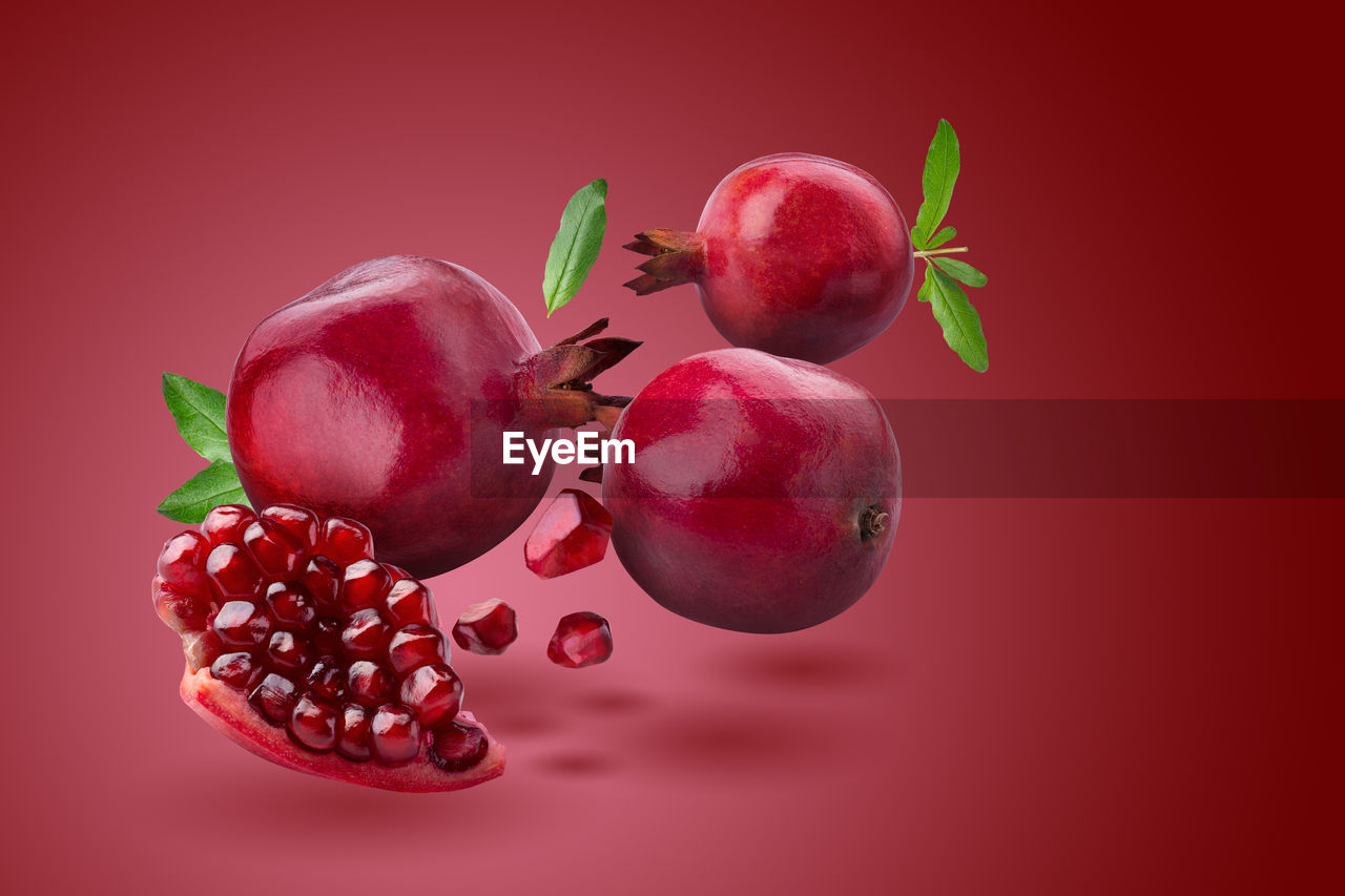 Ripe pomegranate fruit on red background.