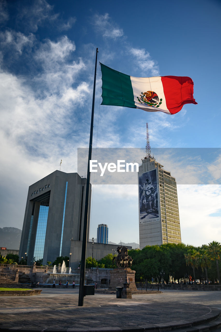 LOW ANGLE VIEW OF FLAG BY BUILDINGS AGAINST SKY