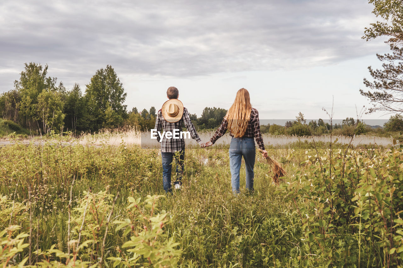 REAR VIEW OF COUPLE WALKING ON FIELD