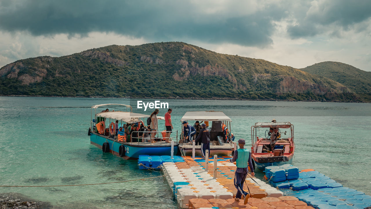 BOATS IN SEA AGAINST MOUNTAIN RANGE