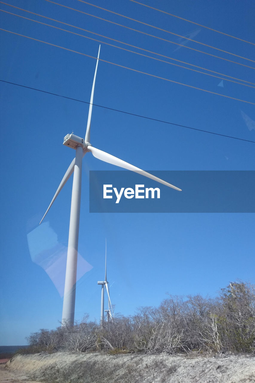 low angle view of windmills on field against sky