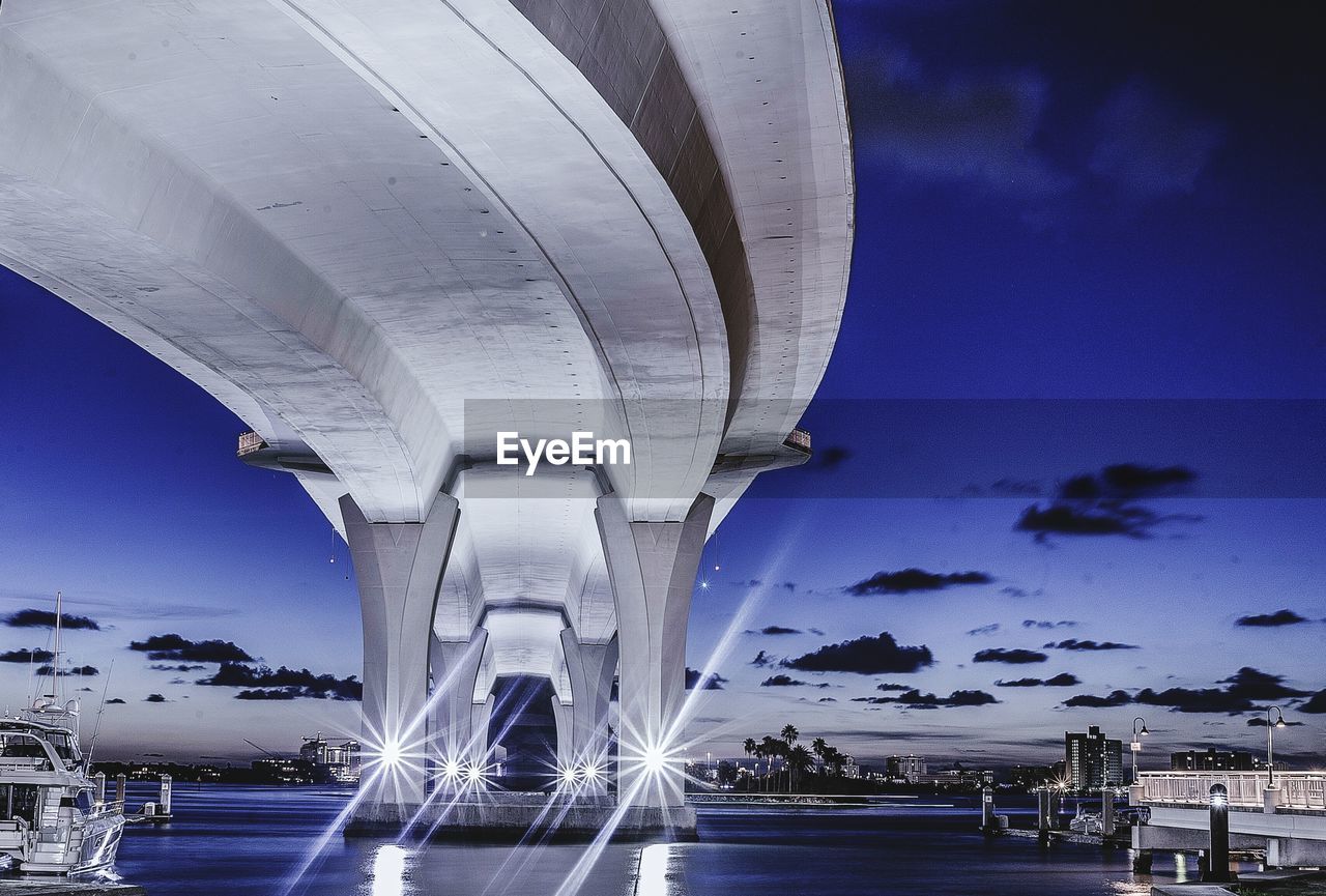 LOW ANGLE VIEW OF ILLUMINATED BRIDGE AT NIGHT