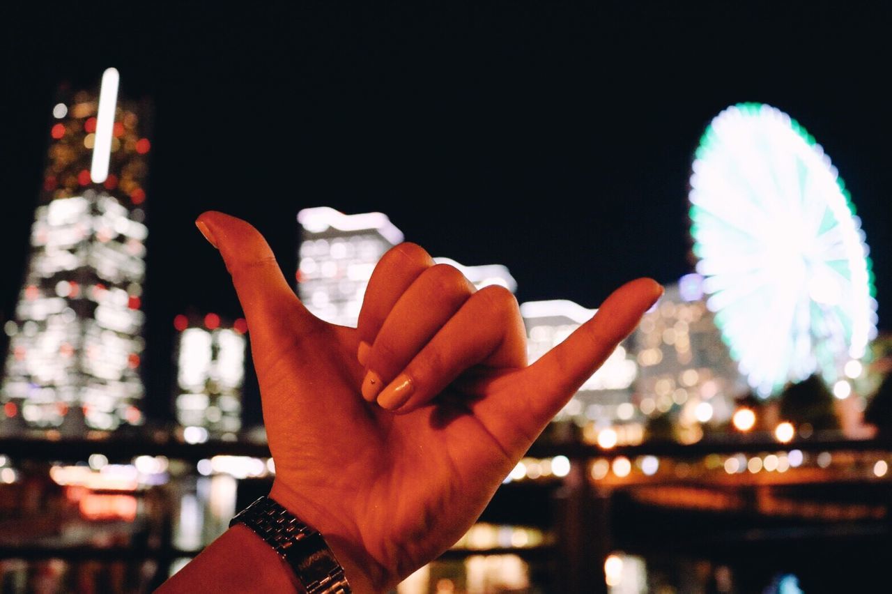 CLOSE-UP OF HUMAN HAND AGAINST ILLUMINATED SKY