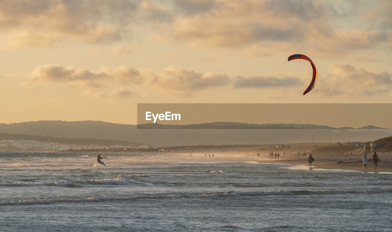 PEOPLE IN SEA AGAINST SKY DURING SUNSET