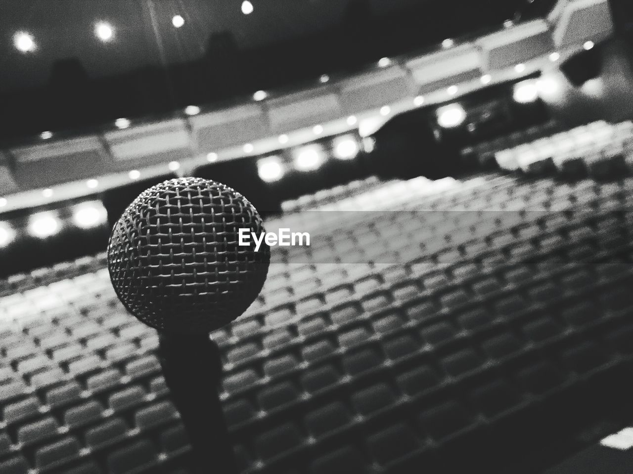 Tilt shot of microphone against empty seats in auditorium