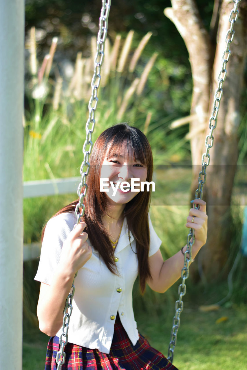 portrait of young woman sitting on swing