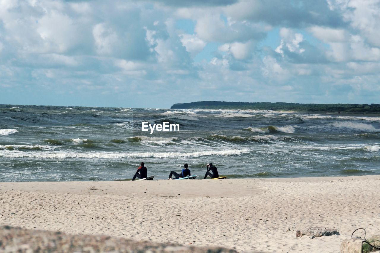 Rear view of friends lying on shore at beach