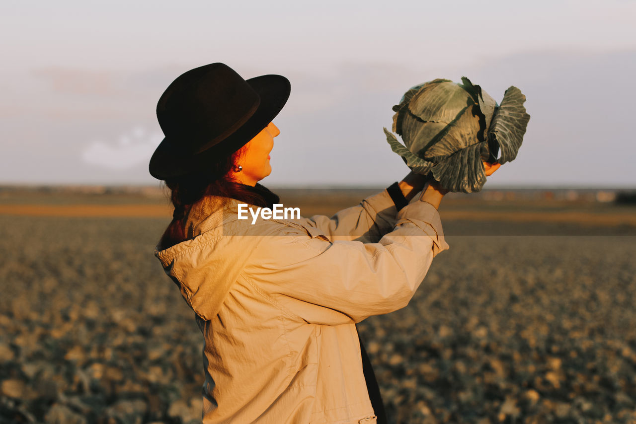 Woman picking cabbage vegetable at field.female farmer working at organic farm. harvesting at autumn