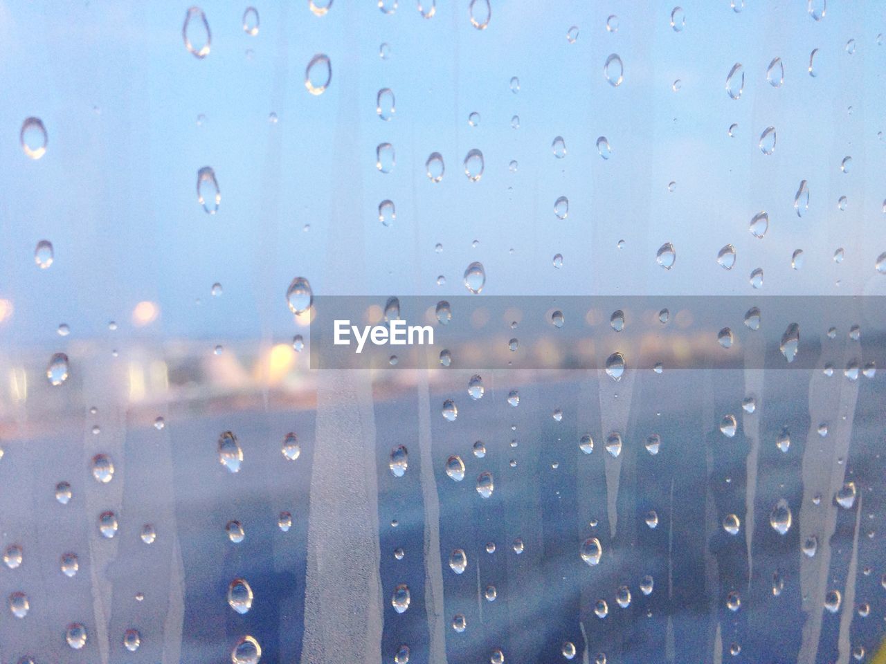 CLOSE-UP OF WATER DROPS ON WINDOW AGAINST SKY