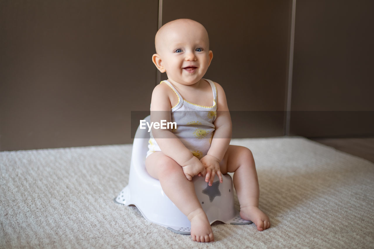 portrait of cute baby boy sitting on floor