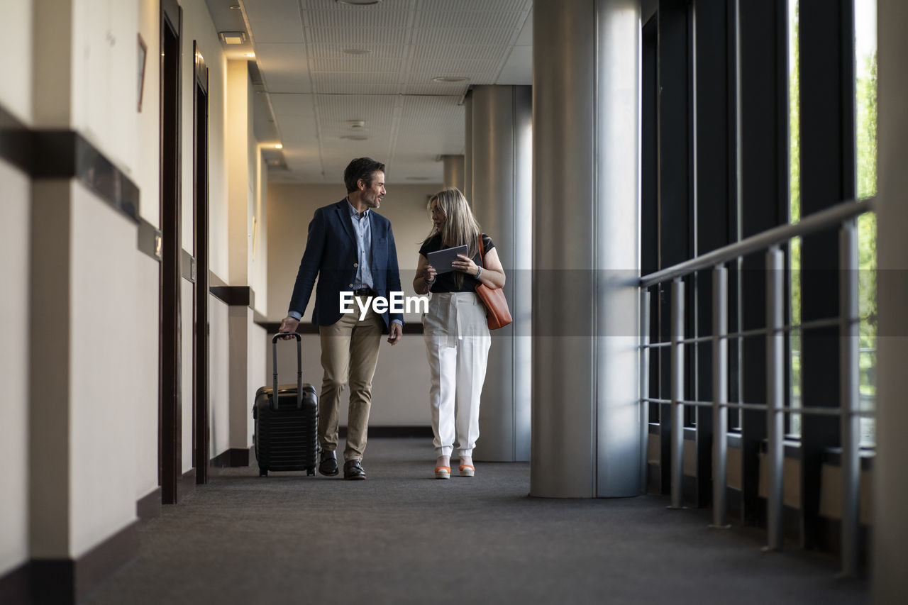 Businesswoman with digital tablet discussing with male freelancer at hotel